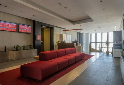 Spacious reception area with red seating and digital screens.