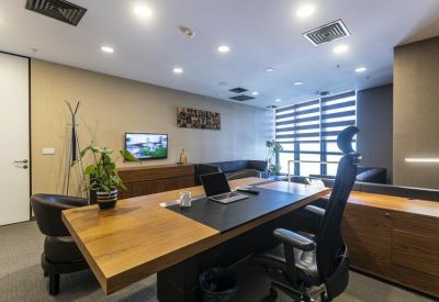 Modern office with a large wooden desk and natural light.