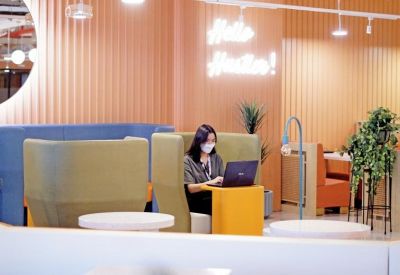 Individual work pod with a yellow desk and high-backed green privacy chair.