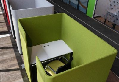Colorful private work pods in green, white, and red lined up along a corridor.