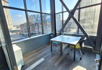 Bright corner meeting space with floor-to-ceiling windows and a simple square table.
