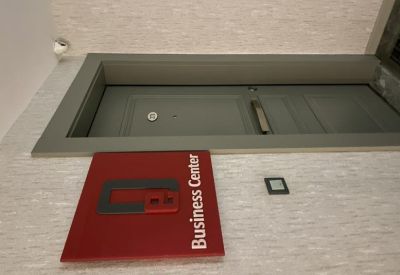 Close-up of a gray door and a red Business Center sign on a textured wall.