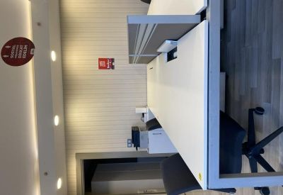 Brightly lit open-plan office desks with gray dividers.