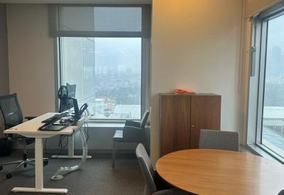 Private office suite with a sit-stand desk and a round wooden meeting table.