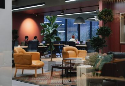 Lounge area with tan leather armchairs and potted trees.