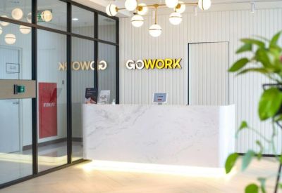 Bright marble reception desk under a modern chandelier with gold signage on a wood-slat wall.