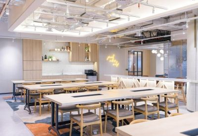 Spacious coworking area with long wooden tables, ergonomic chairs, and modern lighting.