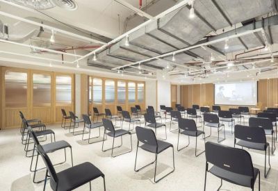 Bright seminar room with rows of black chairs and a projection screen.