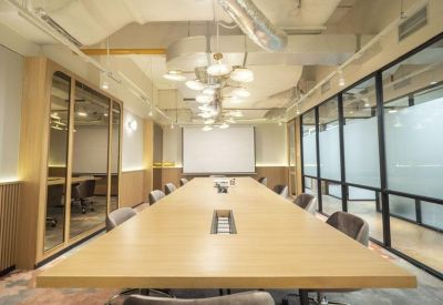 Long wooden boardroom table under a modern cluster chandelier in a bright meeting room.