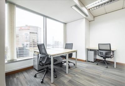 Bright corner office with two workstations and views of neighboring skyscrapers.