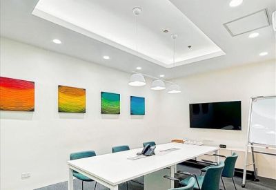 Brightly lit meeting room with a large white table, teal chairs, and colorful abstract wall art.