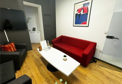 Casual breakout area with a red sofa, white coffee table, and abstract art.