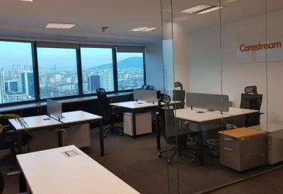 Open-plan office space with multiple white desks and large windows overlooking the city.