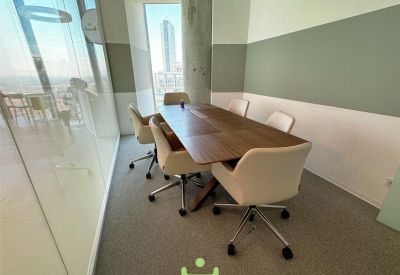 Small meeting room with wooden table, cream chairs, and a window overlooking the city.