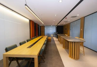 Long wooden communal table under a sleek linear light fixture.