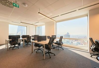 Bright office space with white desks and floor-to-ceiling windows.