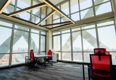 Open office workspace with red chairs and unique geometric ceiling light fixtures under a high glass roof.