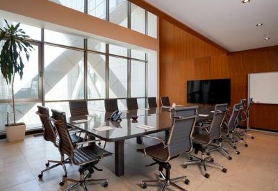 Bright conference room with a large glass table, mesh chairs, and wood paneling overlooking the city.