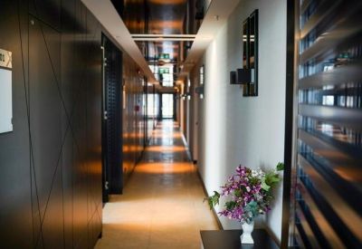 Modern hallway with dark paneled walls, reflective ceilings, and a colorful floral arrangement.