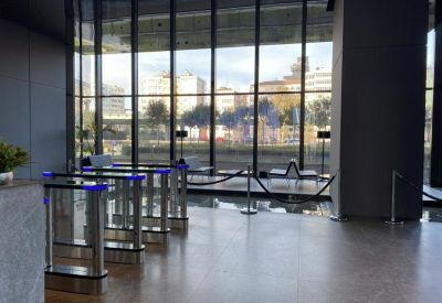 Secure building lobby featuring glass turnstiles and large windows.