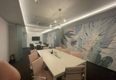 Bright boardroom with a white table, tan chairs, and tropical leaf wall art.