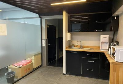 Modern office kitchen with black cabinetry, wooden countertops, and a water dispenser.