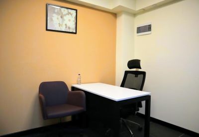 Private office suite featuring an orange accent wall and a white desk with a black mesh chair.