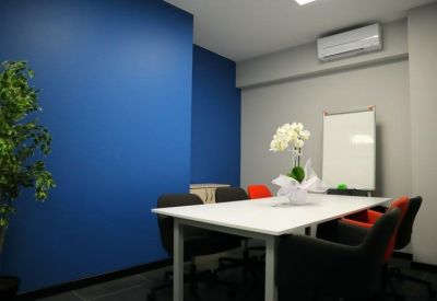 Meeting room with a blue accent wall, white table, and black and red chairs.