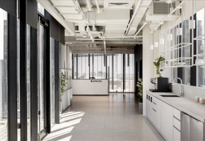 Sleek office kitchen and reception hallway with white cabinetry and exposed ceiling.