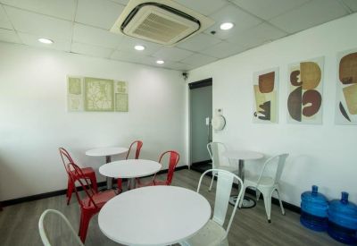 Bright breakroom with white circular tables and vibrant red chairs.