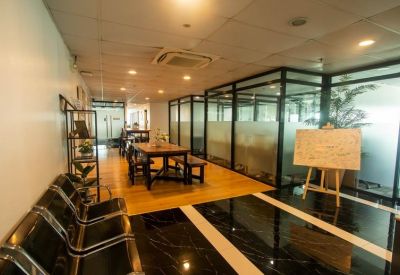 Spacious reception area with warm wood flooring and glass-partitioned offices.