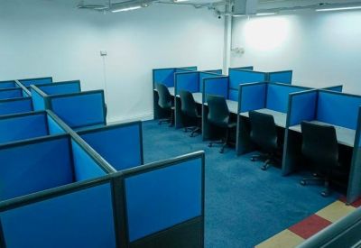 Large open-plan workspace with multiple blue-partitioned cubicles and black chairs.