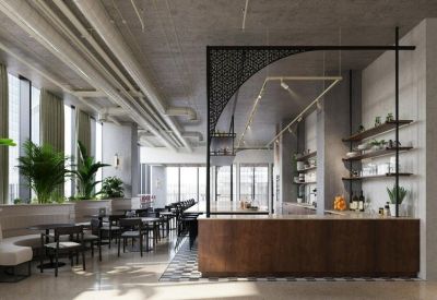 Modern café and lounge area with industrial ceilings, indoor plants, and a wooden service counter.