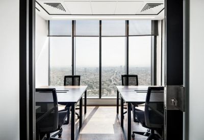 Minimalist private office suite for four people with floor-to-ceiling windows overlooking the city.