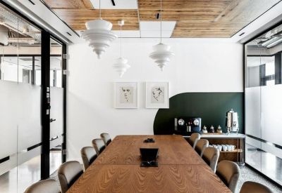 Sleek conference room with a large wood table, tiered pendant lights, and a dark green accent wall.