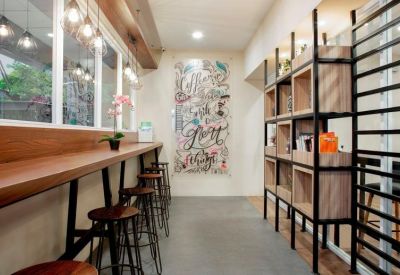 Bright communal lounge featuring a long wooden breakfast bar, stools, and colorful wall art.