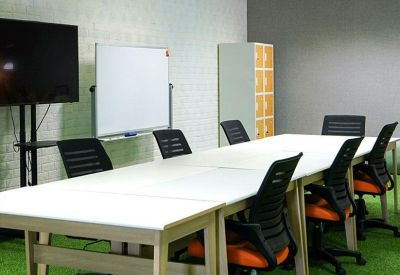 Bright meeting room featuring a long white table and green turf-style flooring.