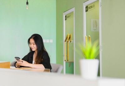 Reception desk area with a green feature wall and frosted glass doors leading to private offices.