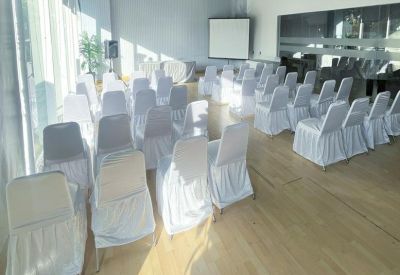Formal event space with several rows of chairs set up in front of a projection screen.