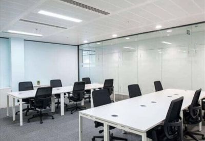 Open-plan workspace with multiple white desks and black ergonomic chairs.