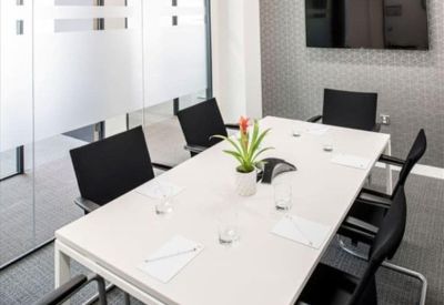 Professional meeting room with a white conference table, black chairs, and a wall-mounted screen.