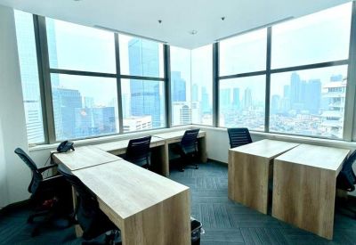 Bright corner office with wooden desks and expansive city skyline views.