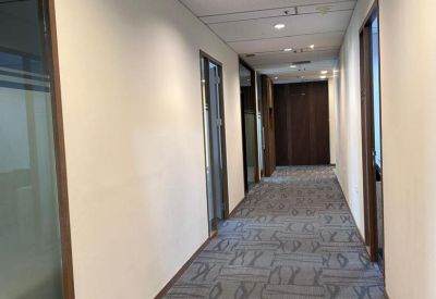 Long office corridor with patterned grey carpet and glass-fronted suites.