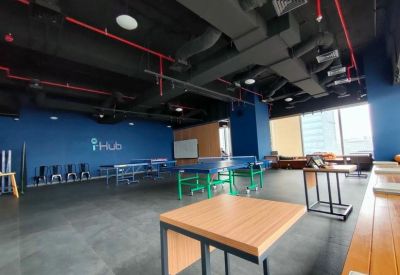 Spacious communal area with blue walls, exposed black ceilings, and ping pong tables.