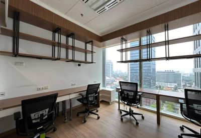 Bright office space with wooden desks, ergonomic chairs, and wall-mounted shelving.