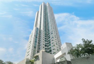 Exterior view of the soaring glass and concrete Menara Batavia tower against a blue sky.