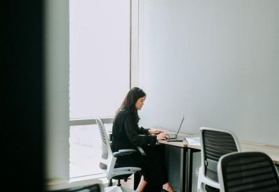 Private office pod with a person working at a desk next to a large window.