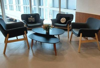 Cozy lounge area featuring charcoal gray armchairs arranged around a two-tier black coffee table.