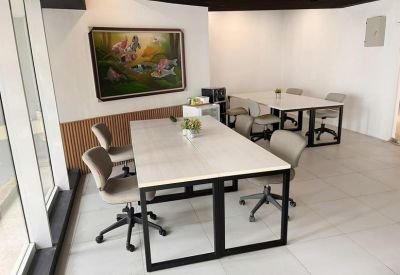 Bright coworking area with white stone-top desks and a colorful painting on the wall.