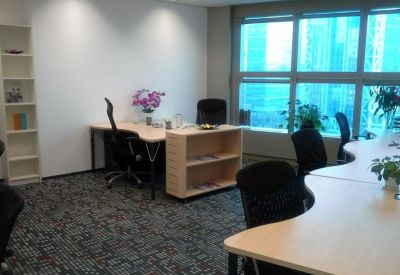 Bright corner office with ergonomic chairs, curved desks, and large windows.